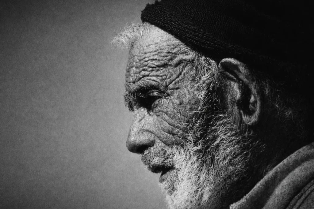 Portrait en noir et blanc d'un homme âgé au visage marqué par le temps, symbolisant la longévité, la force et la résistance des habitants des régions côtières du Portugal grâce à une alimentation saine