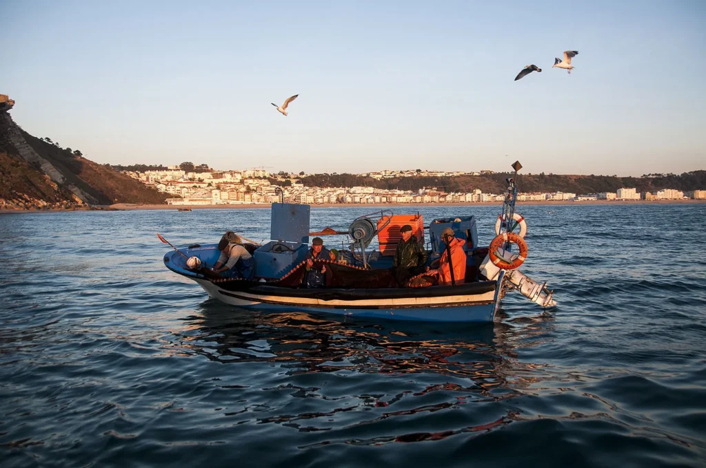 Pêcheurs pratiquant la petite pêche artisanale au large de Nazaré, sur un bateau côtier