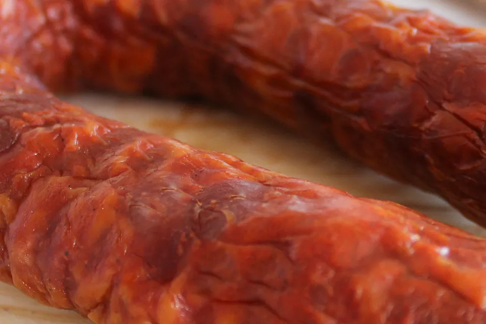 Macro et gros plan sur le piquant du Chouriço portugais artisanal 220 g de Quintinha d'Aldeia, révélant la texture dorée, le fumage traditionnel et les détails de la chair épicée.