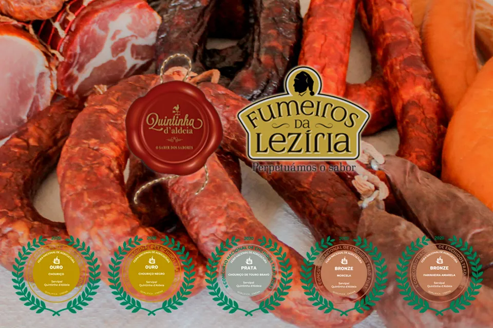Assortiment de charcuteries traditionnelles portugaises (chouriço, morcela, farinheira) sous les logos Quintinha d'Aldeia et Fumeiros da Lezíria, affichant 5 médailles du X Concurso Nacional de Enchidos Tradicionais Portugueses 2020 (médailles d'or pour Chouriço et Chouriço Negro, argent pour Touro Bravo, bronze pour Morcela et Farinheira Amarela).