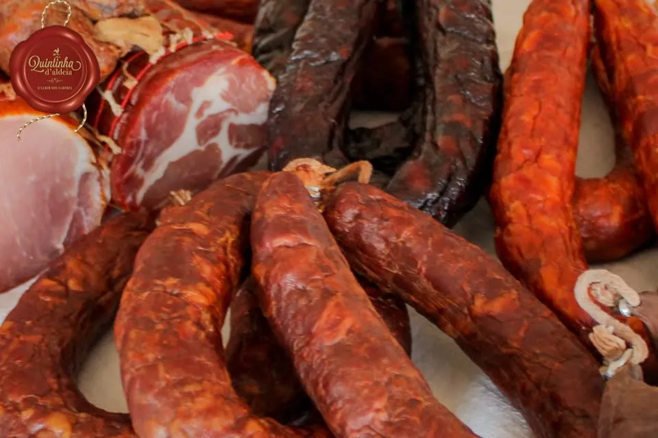 Gros plan sur un assortiment de charcuteries traditionnelles portugaises incluant chouriços et copa par Quintinha d'Aldeia.