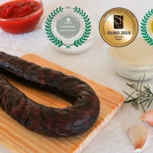 Chouriço Noir Mouro artisanal de Quintinha d'Aldeia sur une planche en bois entouré d'ingrédients et affichant ses médailles de concours (Argent 2022, Or 2019, Or 2020).
