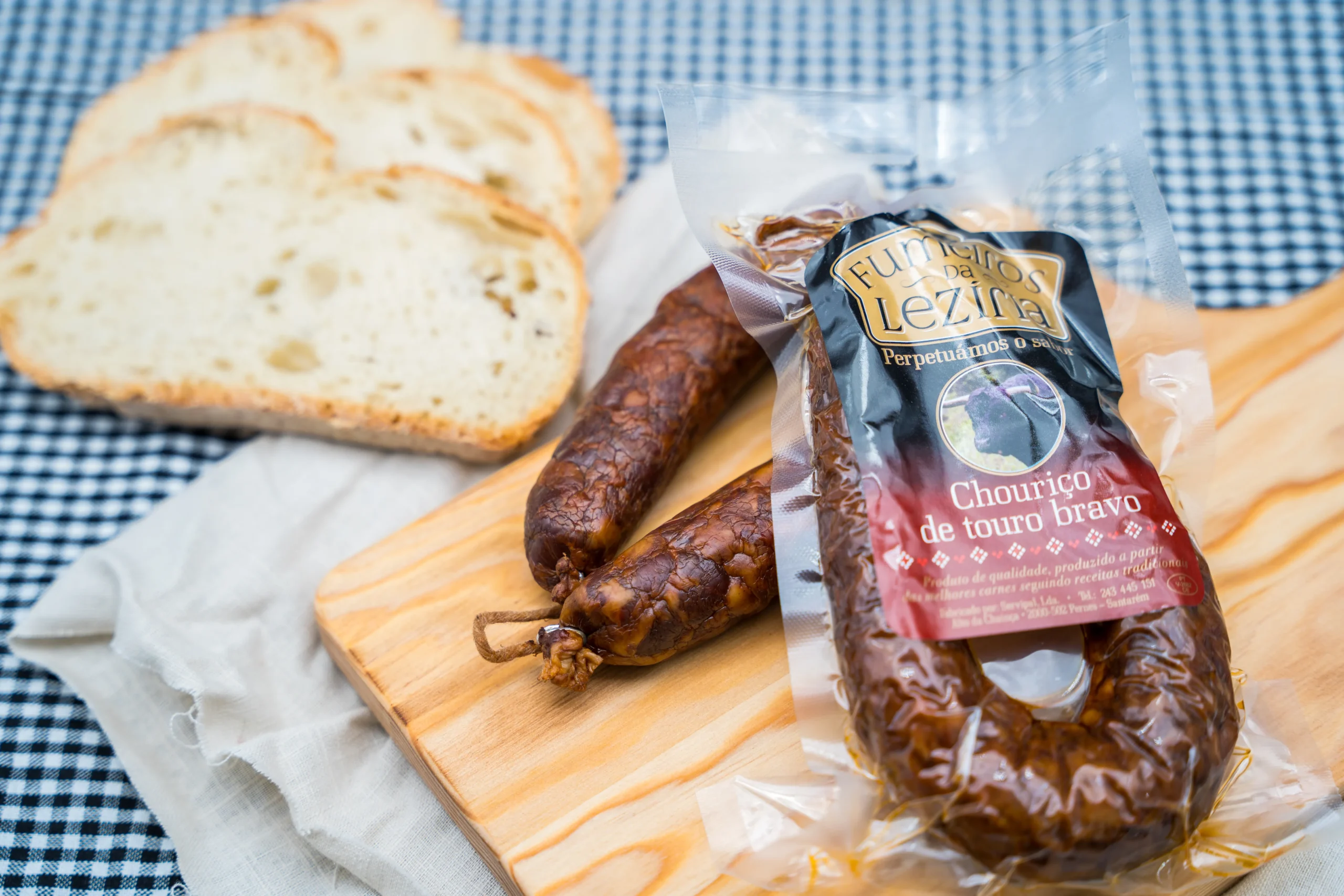 Paquet de Chouriço de Touro Bravo chorizo de taureau brave portugais emballé sous vide à côté de saucissons fumés et tranches de pain sur planche en bois.