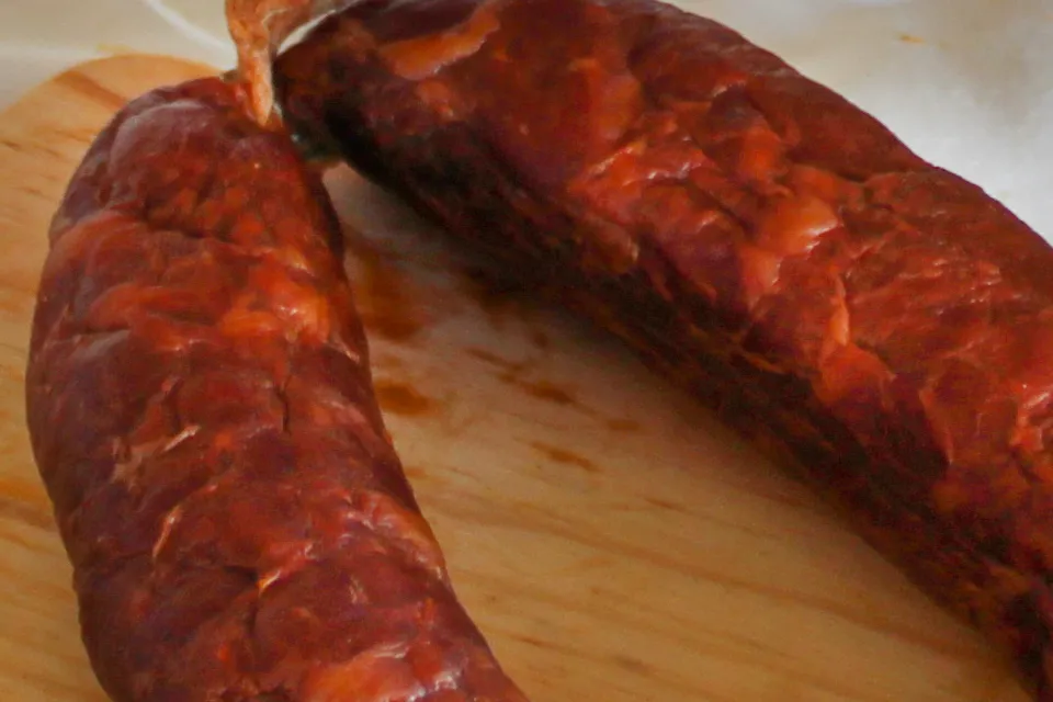 Gros plan sur la texture d'un Chouriço de Touro Bravo chorizo de taureau brave fumé traditionnel de Quintinha d'Aldeia posé sur une planche en bois.