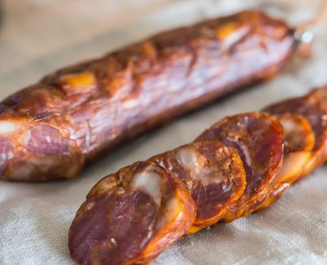 Rondelles et tranches fines de Chouriço de Touro Bravo chorizo de taureau brave fumé artisanal de Quintinha d'Aldeia servies sur linge rustique.