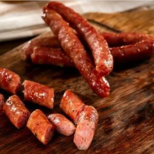 Petites saucisses fumées portugaises Linguiça en pack de 300 g de Quintinha d'Aldeia, entières et découpées en rondelles sur une planche en bois rustic.
