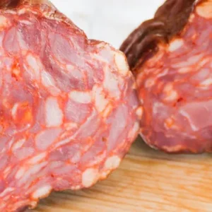 Gros plan sur la coupe transversale du Paiola gros saucisson sec fumé portugais de Quintinha d'Aldeia dévoilant la texture et le marbrage de la viande.
