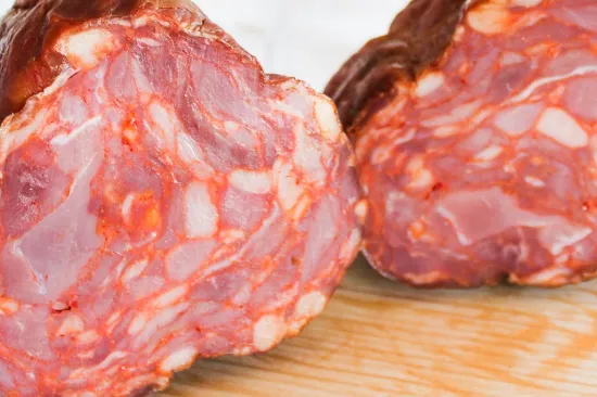 Gros plan sur la coupe transversale du Paiola gros saucisson sec fumé portugais de Quintinha d'Aldeia dévoilant la texture et le marbrage de la viande.