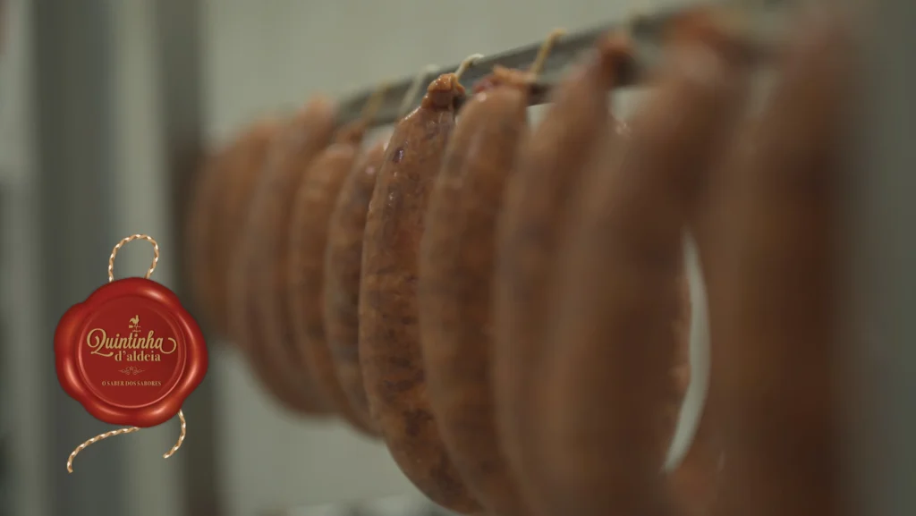 Alignement de chouriços artisanaux suspendus en cours de séchage et fumage traditionnel chez Quintinha d'Aldeia.